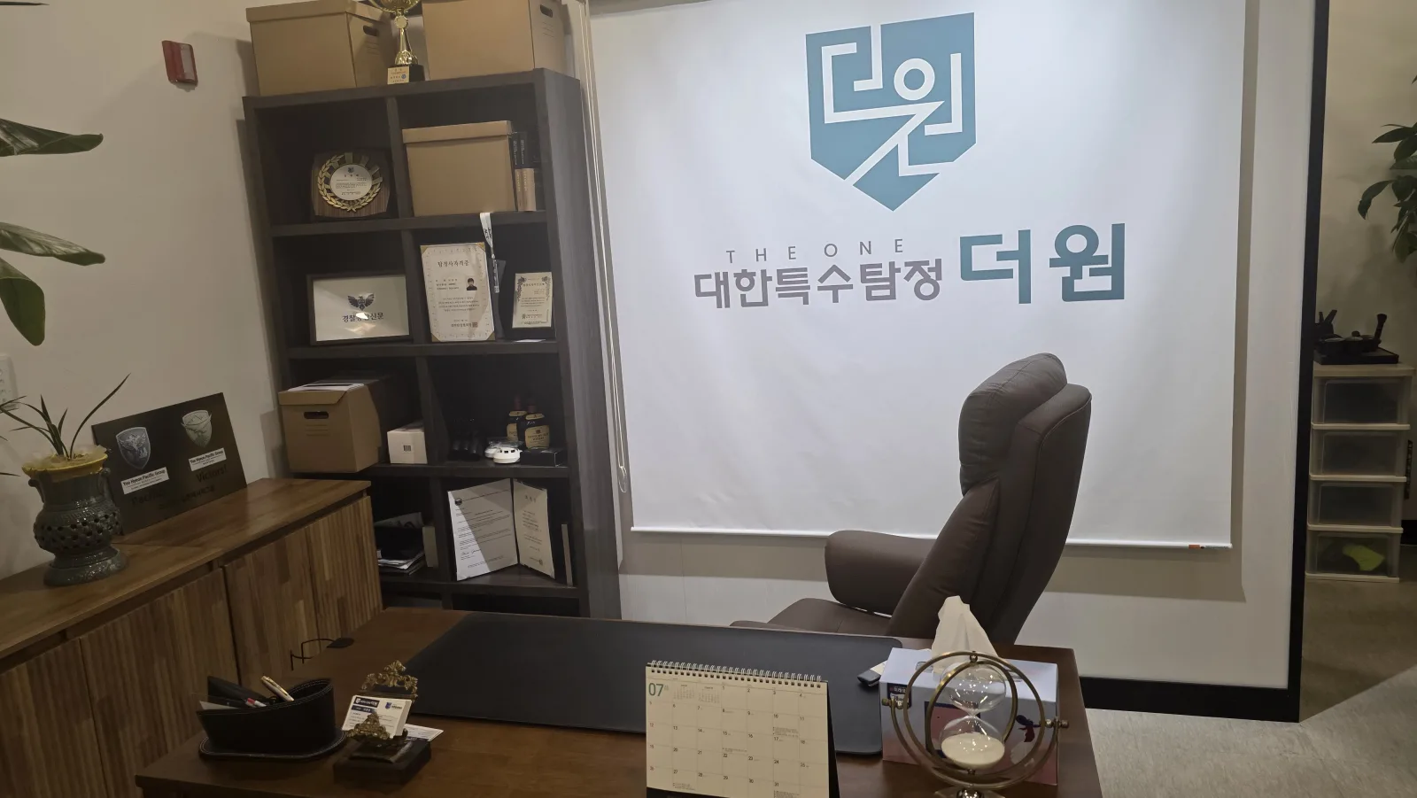 대한특수탐정 더원 사무실 로고 배너와 상패 진열장